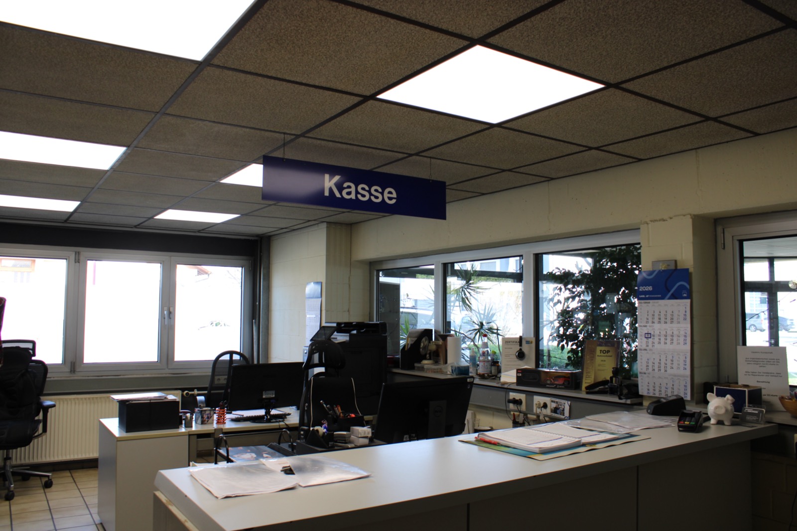 Büro mit Tresen, Arbeitsplätzen und Kasse-Schild