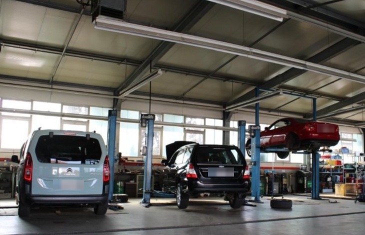 Weite Werkstatthalle mit Fahrzeugen auf Hebebühnen